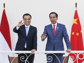 Chinese Premier Li Keqiang, left, and Indonesian President Joko Widodo wave during their meeting at the presidential palace in Bogor, West Java, Indonesia, Monday, May 7, 2018. Li is visiting Indonesia to tighten bilateral relationship between the two countries.