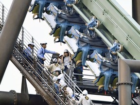 In this Tuesday, May 1, 2018, photo, passengers are rescued from the stopped Flying Dinosaur rollercoaster at Universal Studios Japan amusement park in Osaka, western Japan. Sixty-four passengers were left hanging in the air for up to two hours after the rollercoaster made an emergency stop. The amusement park said the rollercoaster's two carriages stalled midway through the 1,100-meter (yard) ride, with riders suspended in a flying position about 30 meters (100 feet) above the ground.