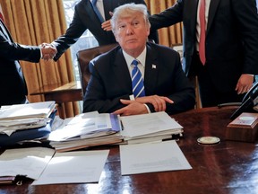 U.S. President Donald Trump sits at his desk after a meeting with Intel CEO Brian Krzanich, left, and members of his staff in the Oval Office of the White House in Washington, Wednesday, Feb. 8, 2017.