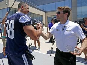 FILE - In this May 30, 2018, file photo, Indianapolis 500 winner Will Power, right, shakes hands with Dallas Cowboys defensive line Tyrone Crawford as Power visits to Dallas Cowboys practice at the team's NFL football training facility in Frisco, Texas. Power's Indianapolis 500 victory turned this week into a whirlwind, but before too long, he'll have another race in Detroit _ and perhaps a more normal routine again.