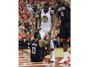 Golden State Warriors forward Draymond Green (23) helps Houston Rockets guard James Harden (13) after he fell to the floor during the second half in Game 7 of the NBA basketball Western Conference finals, Monday, May 28, 2018, in Houston.