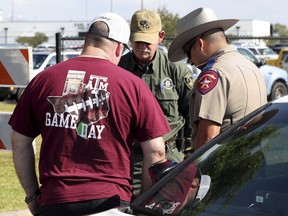 Chris Tucker, left, of Spring, Texas prays with law enforcement officers at Santa Fe High School in Santa Fe, Texas, on Saturday, May 19, 2018. Students and teachers were allowed back to parts of the school to retrieve their belongings Saturday. A gunman opened fire inside the school Friday, May 18, 2018, killing several people.