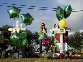 Women visit a memorial for the Santa Fe High School shooting victims outside the school Wednesday, May 23, 2018, in Santa Fe, Texas.