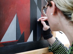 In this Thursday, April 12, 2018 photo, Laura Hartman, a conservator at the Dallas Museum of Art works on a Ida O'Keeffe painting at the DMA in Dallas. The abstract painting of a lighthouse caught the eye of Dallas Museum of Art curator Sue Canterbury as she visited a private collector about five years ago. Struggling to identify the artist, she walked up to the work and looked at the signature. She says she had the same reaction others do when she mentions the artist now: "Ida O'Keeffe?" Canterbury has spent the ensuing years tracking down the works of renowned artist Georgia O'Keeffe's sister Ida Ten Eyck O'Keeffe for an exhibit.