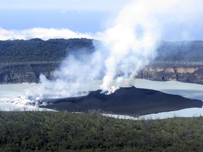 Steam rises from the volcanic cone that has formed in Lake Vui near the summit of Ambae Island, Vanuatu. The Pacific nation of Vanuatu is preparing to permanently evacuate the entire population of one of its islands as thick ash spewing from a volcano kills crops, dirties water supplies and fouls the air.
