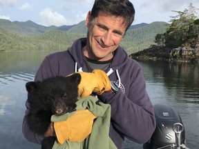 John Forde, the co-owner of the Whale Centre in Tofino, B.C., holds an orphaned black bear cub near Tofino in a handout photo.