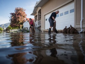 Linda Sylbester, left, and her husband Rick place sandbags around their home as water from Osoyoos Lake floods the street and properties in their neighbourhood, in Osoyoos, B.C., on Saturday May 12, 2018. Thousands of people have been evacuated from their homes in British Columbia's southern interior as officials warn of flooding due to extremely heavy snowpacks, sudden downpours and unseasonably warm temperatures.