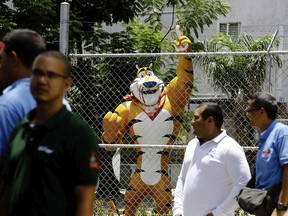 A statue of Kellogg's mascot, Tony the Tiger, stands behind the Kellogg's factory's fence, as workers gather outside in Maracay, Venezuela, Tuesday, May 15, 2018.