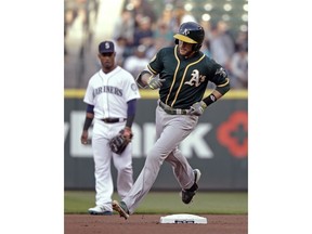 Oakland Athletics' Jed Lowrie, right, rounds the bases with a home run as Seattle Mariners shortstop Jean Segura watches in the first inning of a baseball game Tuesday, May 1, 2018, in Seattle.