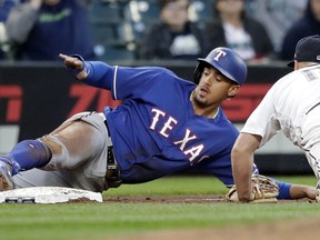 Texas Rangers' Ronald Guzman, left, stretches to keep a toe on third base as Seattle Mariners third baseman Kyle Seager reaches to tag him during the fifth inning of a baseball game Wednesday, May 30, 2018, in Seattle. Guzman was safe on the play, having advanced from second on a wild pitch by Mariners starter James Paxton.