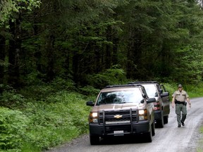Washington State Fish and Wildlife Police leave the scene on a remote King County road near the site of a fatal cougar attack Saturday May 19, 2018 in East King County, Wash.  One man was killed and another seriously injured when they encountered a cougar Saturday while mountain biking in Washington state, officials said.