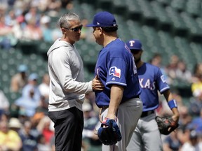 Texas Rangers trainer Kevin Harmon, left, touches the stomach of starting pitcher Bartolo Colon after Colon was hit with a ball hit by Seattle Mariners' Jean Segura during the fourth inning of a baseball game, Wednesday, May 16, 2018, in Seattle. Colon stayed in the game. The Rangers won 5-1.