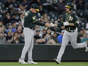 Oakland Athletics' Stephen Piscotty, right, greets third base coach Matt Williams after Piscotty hit a solo home run during the fifth inning of a baseball game against the Seattle Mariners, Thursday, May 3, 2018, in Seattle.