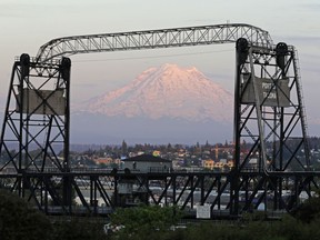 In this May 7, 2018 photo, Mount Rainier is seen at dusk and framed by the Murray Morgan Bridge in downtown Tacoma, Wash. The eruption of the Kilauea volcano in Hawaii has geologic experts along the West Coast warily eyeing the volcanic peaks in Washington, Oregon and California, including Rainier, that are part of the Pacific Ocean's ring of fire.