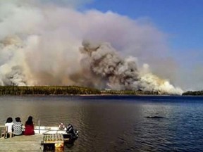 People from the Paungassi First Nation watch a fire burning in Little Grand Rapids, Manitoba.