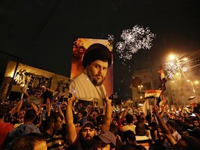 FILE - In this May 14, 2018, file photo, followers of Shiite cleric Muqtada al-Sadr, seen in the poster, celebrate in Tahrir Square, Baghdad, Iraq. Fourteen years after Muqtada al-Sadr's militias fought and killed American troops who had invaded Iraq, the United States is preparing to work hand in hand with the charismatic Shiite cleric and his movement. Following an upset Iraqi election, the U.S. is hoping to find common cause with al-Sadr in curtailing Iran's influence.