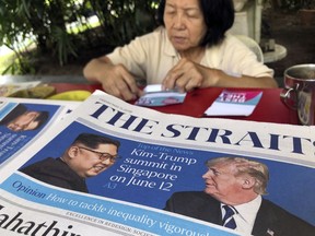 FILE - In this May 11, 2018, file photo, a news vendor counts her money near a stack of newspapers with a photo of U.S. President Donald Trump, right, and North Korea's leader Kim Jong Un on its front page  in Singapore. U.S. Weeks from his North Korea summit, President Donald Trump is staring down a dealmaker's worst nightmare: overpromising and under-delivering.