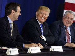 In this April 5, 2018, file photo, U.S. President Donald Trump smiles during a roundtable discussion on tax policy, in White Sulphur Springs, W.Va., with U.S. Rep. Evan Jenkins, R-W.Va., left, and West Virginia Attorney General Patrick Morrisey.