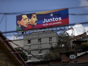 An election campaign billboard shows Venezuela's late President Hugo Chavez, left, with President Nicolas Maduro and the Spanish phrase "Together everything is possible" on top of an apartment building in Caracas, Venezuela, Wednesday, May 16, 2018. Despite die-hard believers, Venezuela's Chavista revolution, named for the late President Hugo Chavez, is being tested like never before in its nearly two decades in power, ahead of the May 20 presidential election in which Maduro seeks reelection.