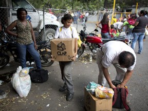 People take their boxes of food staples, such as beans, rice, tuna and powdered milk, provided by the government program "CLAP," which stands for Local Committees of Supply and Production, in Caracas, Venezuela, Wednesday, May 16, 2018. Years of mismanagement have steadily eroded the once-robust oil industry, Venezuela's chief source of income, and the squeeze of financial sanctions by the Trump administration is choking the cash-starved government as it struggles to feed its people.