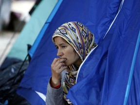 A migrant women from Afghanistan peers from the tent in the park across from The City Hall, in Sarajevo, Bosnia, Thursday, May 17, 2018. Thousands of migrants have been stuck in the Balkans while trying to reach Western Europe. Hundreds have been camping in the Bosnian capital of Sarajevo where a make-shift tent settlement has sprouted in a city park.