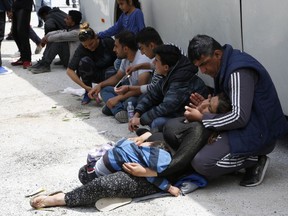 A migrant man comfort his wife who has lost consciousness at the Ivan sedlo, 30 kms south of Sarajevo, on Friday, May 18, 2018. A convoy of buses with around 270 migrants, including children, has been blocked in central Bosnia, reflecting the confusion in the war-scarred Balkan country as it struggles to cope with the influx.