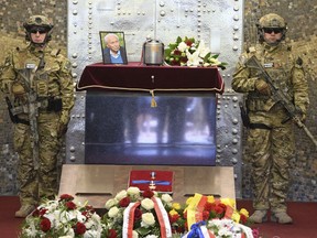 Polish Army soldiers in combat gear stand next to the urn with ashes of WWII hero Stanislaw Likiernik during the funeral ceremony at the Powazki cemetery, in Warsaw, Poland, Monday, May 21, 2018.