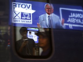 An electronic display panel advertising images of Malaysian Prime Minister Najib Razak and his ruling National Front coalition is reflected on a subway train in Kuala Lumpur, Malaysia, Monday, May 7, 2018. Malaysian scandal-plagued Najib is seeking a third term in office during the May 9 general election, but faces an unprecedented challenge from a rejuvenated opposition led by his former mentor and strongman Mahathir Mohamad.