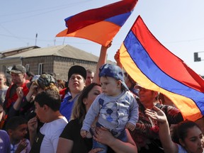 Supporters of the opposition lawmaker Nikol Pashinian wave Armenian national flags as they block a road to the airport just outside Yerevan, Armenia, Wednesday, May 2, 2018. Pashinyan has urged his supporters to block roads, railway stations and airports on Wednesday after the governing Republican Party voted against his election as prime minister.