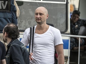 In this photo taken on Friday, May 31, 2013, Arkady Babchenko, 41, who had been scathingly critical of the Kremlin in recent years, stands at a police bus during an opposition rally in Moscow, Russia. Police in the capital of Ukraine say a Russian journalist has been shot and killed at his Kiev apartment. Ukrainian police said Arkady Babchenko's wife found him bleeding at the apartment on Tuesday, May 29, 2018 and called an ambulance, but Babchenko died on the way to a hospital.