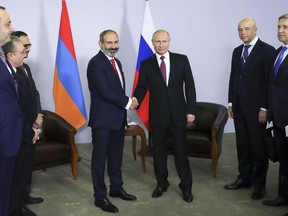 Armenian Prime Minister Nikol Pashinian, left, shakes hands with Russian President Vladimir Putin during their meeting in the Black Sea resort of Sochi, Russia, Monday, May 14, 2018.
