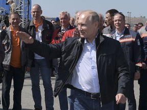 Russian President Vladimir Putin gestures while speaking to a group of workers after driving a truck to officially open the much-anticipated bridge linking Russia and the Crimean peninsula the opening ceremony near in Kerch, Crimea, Tuesday, May 15, 2018. Putin has taken the wheel of a truck to officially open the much-anticipated bridge linking Russia's south and the Crimean peninsula that Russia annexed from Ukraine in 2014.