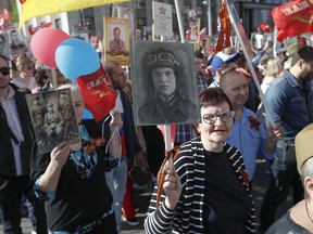 People carry portraits of relatives who fought in World War II, and Russian and Soviet flags, during the Immortal Regiment march along the Red Square in Moscow, Russia, Wednesday, May 9, 2018, celebrating 73 years since the end of WWII and the defeat of Nazi Germany.