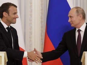 Russian President Vladimir Putin, right, and French President Emmanuel Macron, shake hands after their joint news conference following the talks at the Konstantin palace with the statue of the Peter The Great in the background just outside St. Petersburg, Russia, Thursday, May 24, 2018. Macron's talks with Putin are set to focus on the U.S. exit from the Iranian nuclear deal, as well as conflict in Syria and Ukraine.