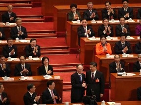 In this March 17, 2018 photo, Chinese President Xi Jinping, center right, shakes hands with Wang Qishan after Wang was elected vice-president during a plenary session of China's National People's Congress (NPC) at the Great Hall of the People in Beijing. Chinese President Xi Jinping is increasingly turning to friend and trusted confidant Wang Qishan to help guide the country's foreign relations as he prepares for a potentially bruising trade fight with the U.S. and competition for leadership in Asia.