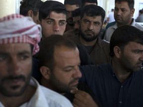 Displaced men from Mosul wait in a queue before casting their ballot in the parliamentary elections at a polling site in a camp for displaced people in Baharka, Iraq,  Saturday, May 12, 2018. Polls opened across Iraq on Saturday in the first national election since the declaration of victory over the Islamic State group.