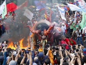 Protesters, mostly workers, burn an effigy depicting President Rodrigo Duterte as a devil, during a rally near the Presidential Palace at the global commemoration of Labor Day Tuesday, May 1, 2018 in Manila, Philippines. For the first time in almost three decades, various labor groups, used to be adversaries, have joined forces for a huge rally to condemn President Rodrigo Duterte for allegedly reneging on his campaign promise to stop the business practice of a few months of hiring workers on a contractual basis, locally known as ENDO or "End of Contract."