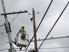 In this May 16, 2018 photo, a worker with Cobra Energy Company, contracted by the Army Corps of Engineers, installs power lines in the Barrio Martorel area of Yabucoa, a town where many people are still without power in Puerto Rico. The Army Corps of Engineers is ending its work to rebuild Puerto Rico's electric grid, despite residents' fears that the island's government won't be able to restore power on its own to more than 16,000 people who remain blacked out eight months after Hurricane Maria.