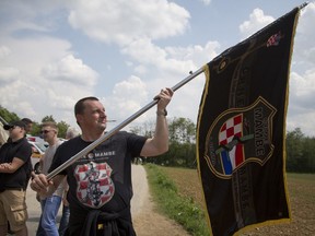 A Croatian war veteran hold his unit's flag which he was prevented to bring to a commemoration ceremony, in Bleiburg, Austria, Saturday, May 12, 2018. Thousands of Croatian far-right supporters have gathered in a field in southern Austria to commemorate the massacre of pro-Nazis by victorious communists at the end of World War II. The controversial annual event was held Saturday amid a surge of far-right sentiments in Croatia, the European Union's newest member.