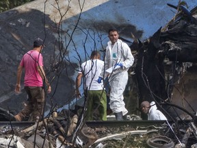 Forensic investigators and Ministry of Interior officers sift through the remains of a Boeing 737 that plummeted into a yuca field with more than 100 passengers on board, in Havana, Cuba, Friday, May 18, 2018. The Cuban airliner crashed just after takeoff from Havana's international airport.