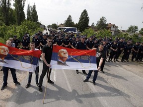 Supporters of Serbian Radical Party leader Vojislav Seselj pose with the Serbian flags that show a photo of Seselj, in front of a police cordon, in the village of Jarak, Serbia, Sunday, May 6, 2018.