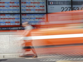 A man walks past an electronic stock board showing Japan's Nikkei 225 index at a securities firm in Tokyo Wednesday, May 16, 2018. Japan's economy shrank at an annualized rate of 0.6 percent in the quarter through March, as private investment and public spending declined, according to Cabinet Office data released Wednesday.