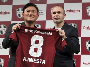 Former Barcelona player Andres Iniesta, right, holds his new uniform with Hiroshi Mikitani, left, owner of Vissel Kobe, during a press conference to join Japan's Vissel Kobe in Tokyo Thursday, May 24, 2018. Iniesta was introduced as the newest member of Japanese club Vissel Kobe on Thursday.