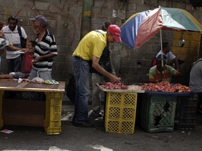 In this May 11, 2018 photo, street vendors selling beef bones wait for customers, in Caracas, Venezuela. The May 20 presidential election plays out as the inflation rate doubles every 35 days and is running near 14,000 percent on an annual basis, according to estimates by the opposition-controlled National Assembly.