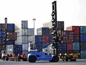 Workers move containers at a port in Qingdao in eastern China's Shandong province Tuesday, May 8, 2018. Official figures show that China's exports expanded by 21.5 percent in April, bouncing back from a contraction the previous month, in a sign of resurgent global demand.(Chinatopix Via AP) CHINA OUT