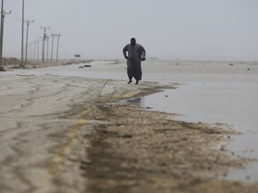 An Omani man walks on the road covered by the flood water after Cyclone Merkunu in Salalah, Oman, Saturday, May 26, 2018. Cyclone Merkunu blew into the Arabian Peninsula on Saturday, drenching arid Oman and Yemen with rain, cutting off power lines and leaving at least one person dead and 40 missing, officials said.