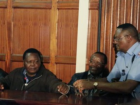 Kenyan police remove handcuffs from the director general of NYS Richard Ndubai, second right, and unidentified man, left as they appear with other suspects accused of corruption, at the Mililani law court in Nairobi, Kenya Tuesday, May 29, 2018. Kenyan authorities have charged 24 officials in what prosecutors call the first stage of investigations into a $79 million corruption scandal that has pressured President Uhuru Kenyatta to crack down on graft.