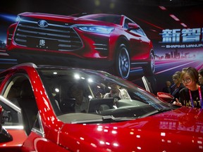 FILE - In this April 25, 2018, file photo, attendees look at the Tang SUV by Chinese automaker BYD after a press conference at the China Auto Show in Beijing. An industry group says Chinese passenger car sales expanded at a faster pace in April 2018 as growth in the world's biggest auto market picked up steam.