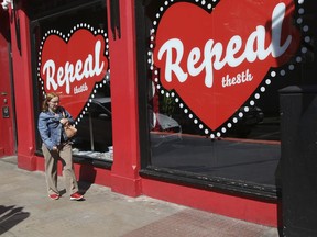 In this May 17, 2018 photo, a woman walks past a "Yes" campaign logo on a shop window in Dublin, Ireland, ahead of the abortion referendum on Friday, May 25.  An abortion debate that has inflamed passions in Ireland for decades will come down to a single question on Friday: yes or no? The referendum on whether to repeal the country's strict anti-abortion law is being seen by anti-abortion activists as a last-ditch stand against what they view as a European norm of abortion-on-demand, while for pro-abortion rights advocates, it is a fundamental moment for declaring an Irish woman's right to choose.