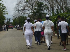 Nurses walk to the site where a Cuban airliner with more than 100 passengers on board plummeted into a yuca field just after takeoff from the international airport in Havana, Cuba, Friday, May 18, 2018.